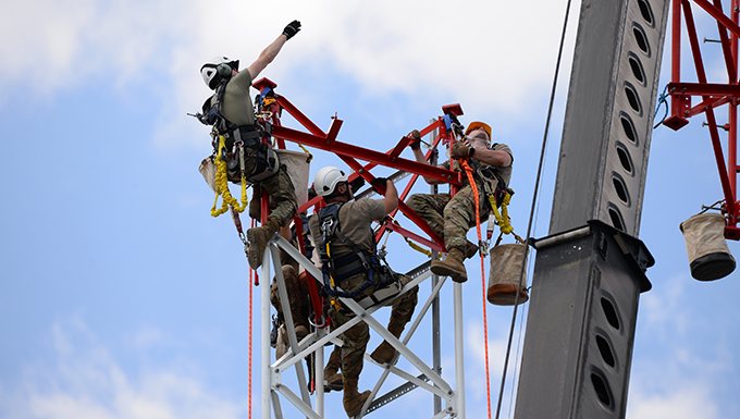An image of Airmen preparing to connect a section of radio communications tower.